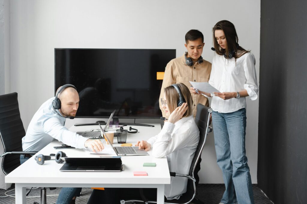 pexels-photo-7682134-7682134 Group of diverse colleagues working together in a modern office environment with headsets and laptops.